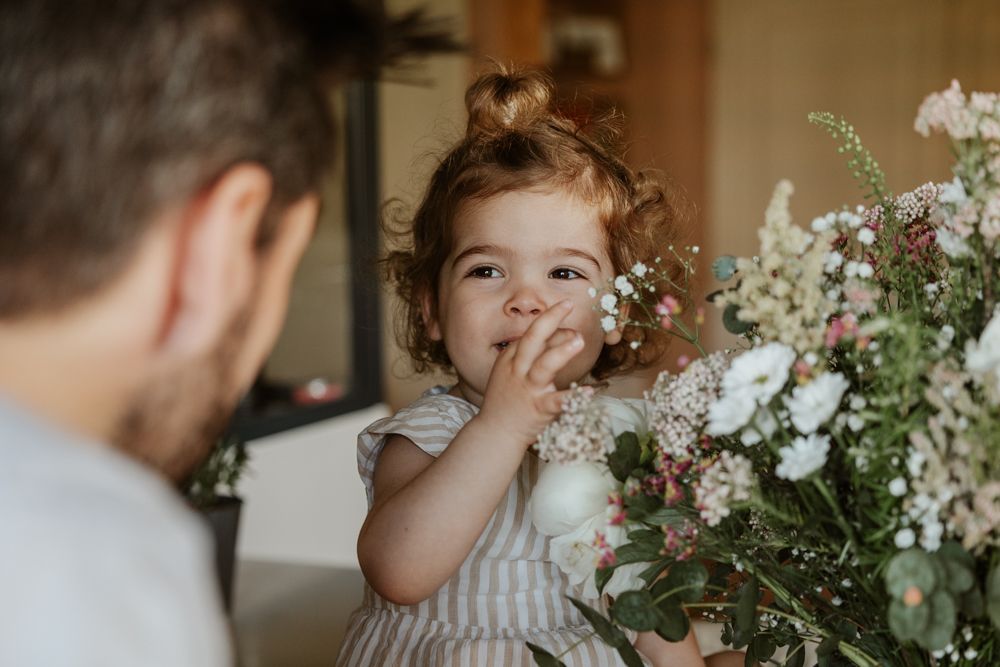 petite fille regarde son papa en découvrant un énorme bouquet de fleurs pendant une séance photo famille à Lille