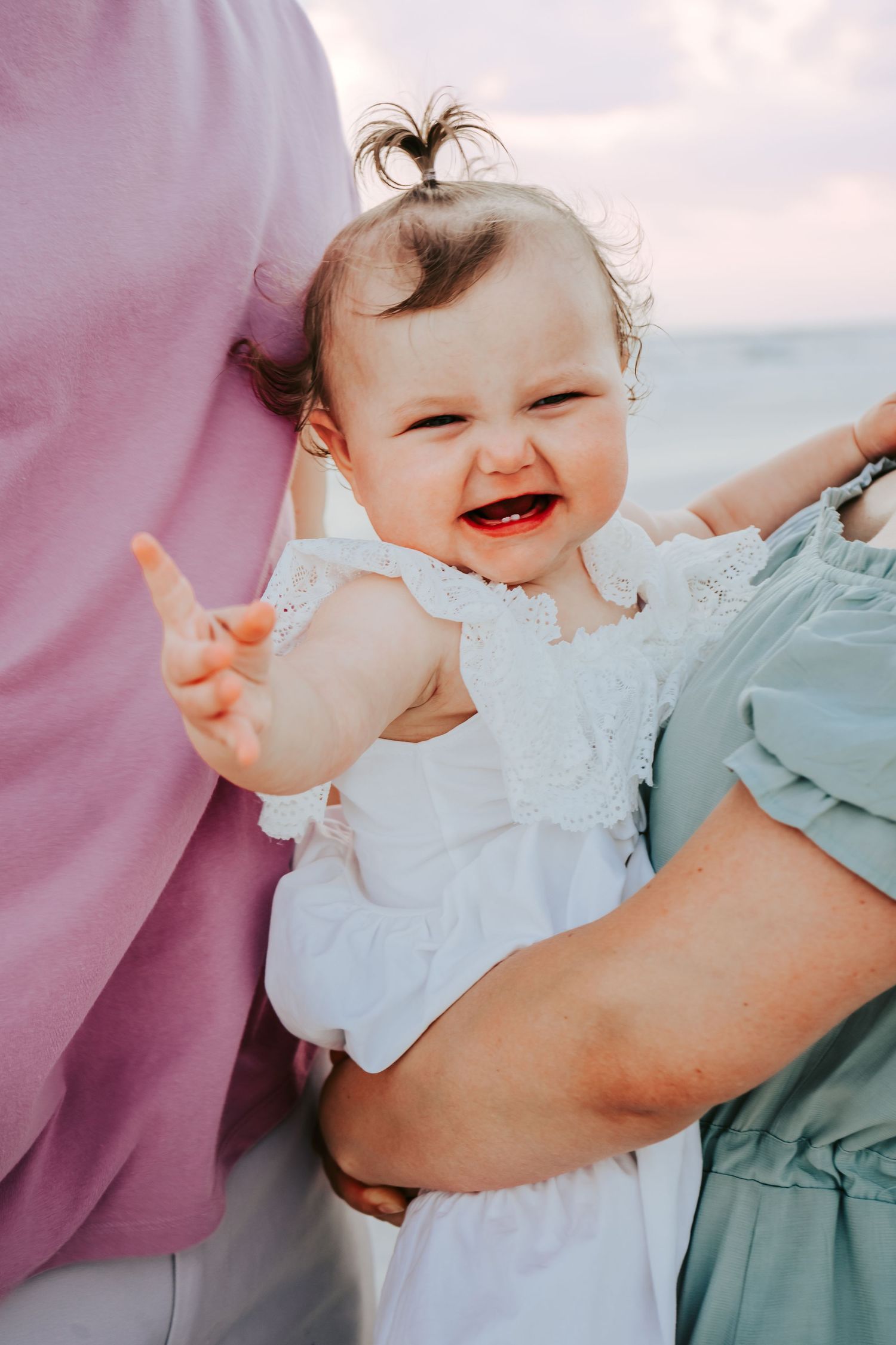 Outdoor Family Session at Indian Rocks Beach in Indian Rocks, FL; baby laughing and pointing at camera