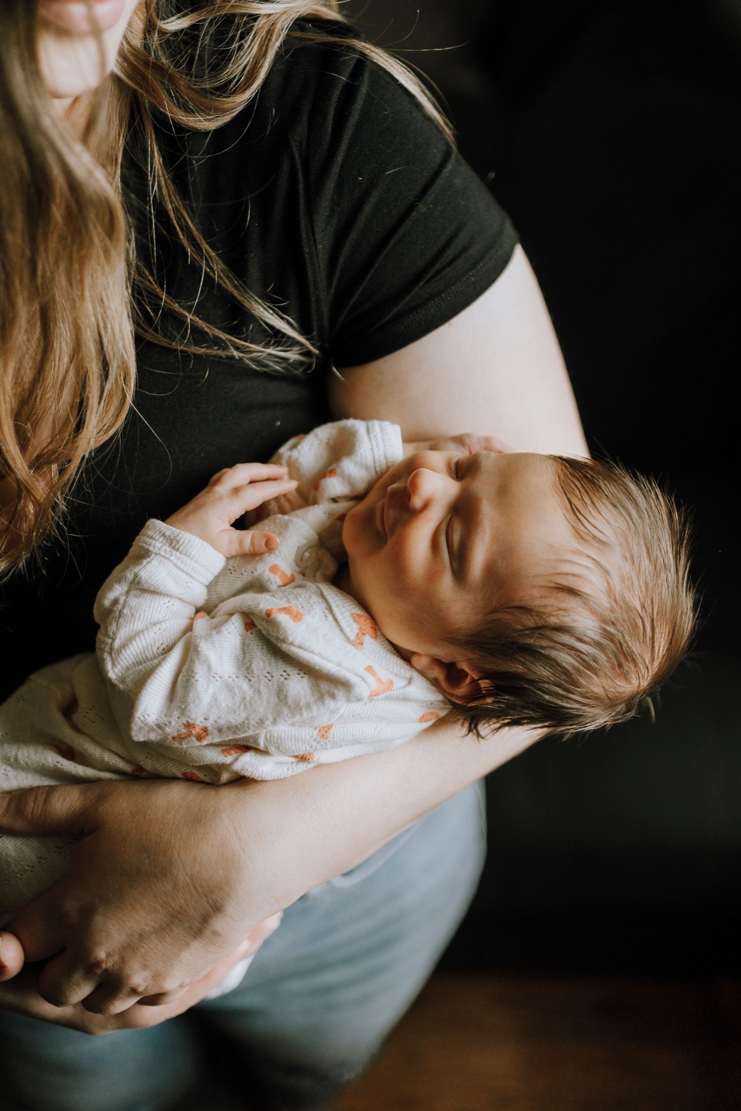 Close-up of sleeping newborn baby being cradled in parent's arms.