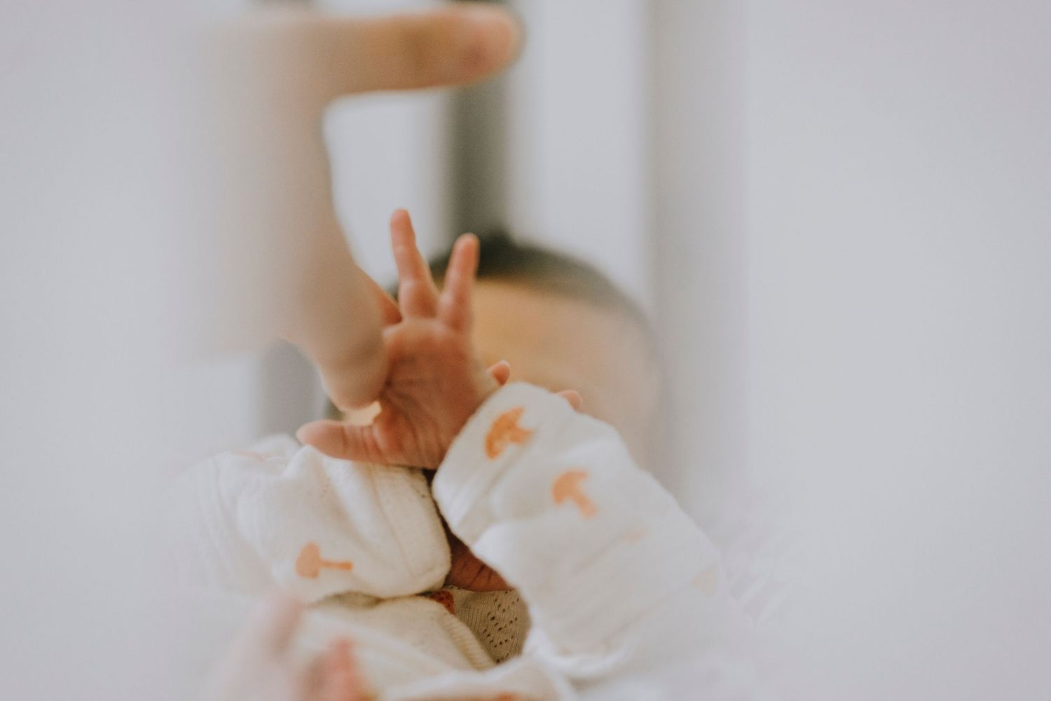 Close-up view of tiny fingers making a peace sign gesture in soft lighting.