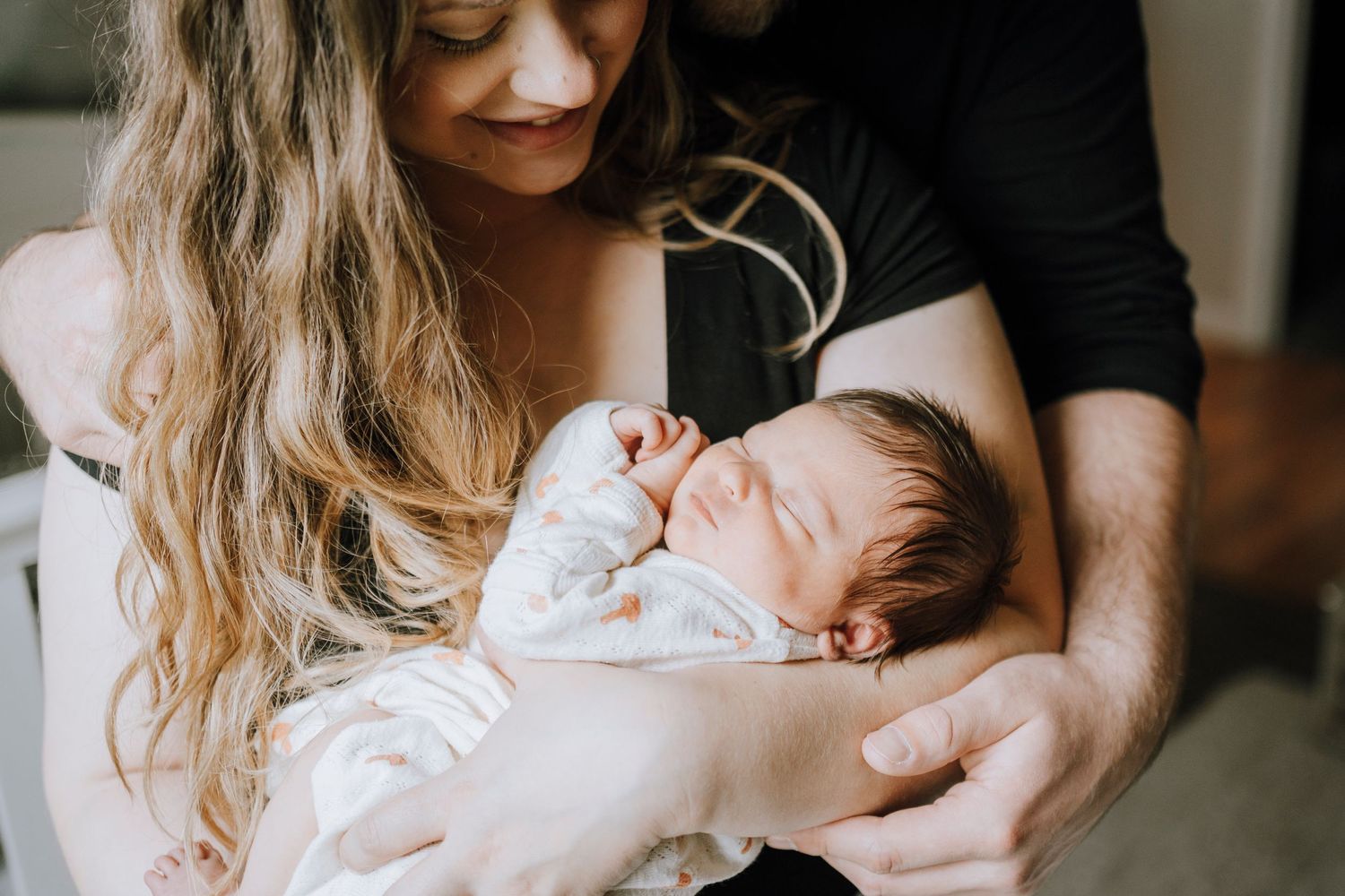 Close-up of sleeping newborn being cradled in gentle embrace.