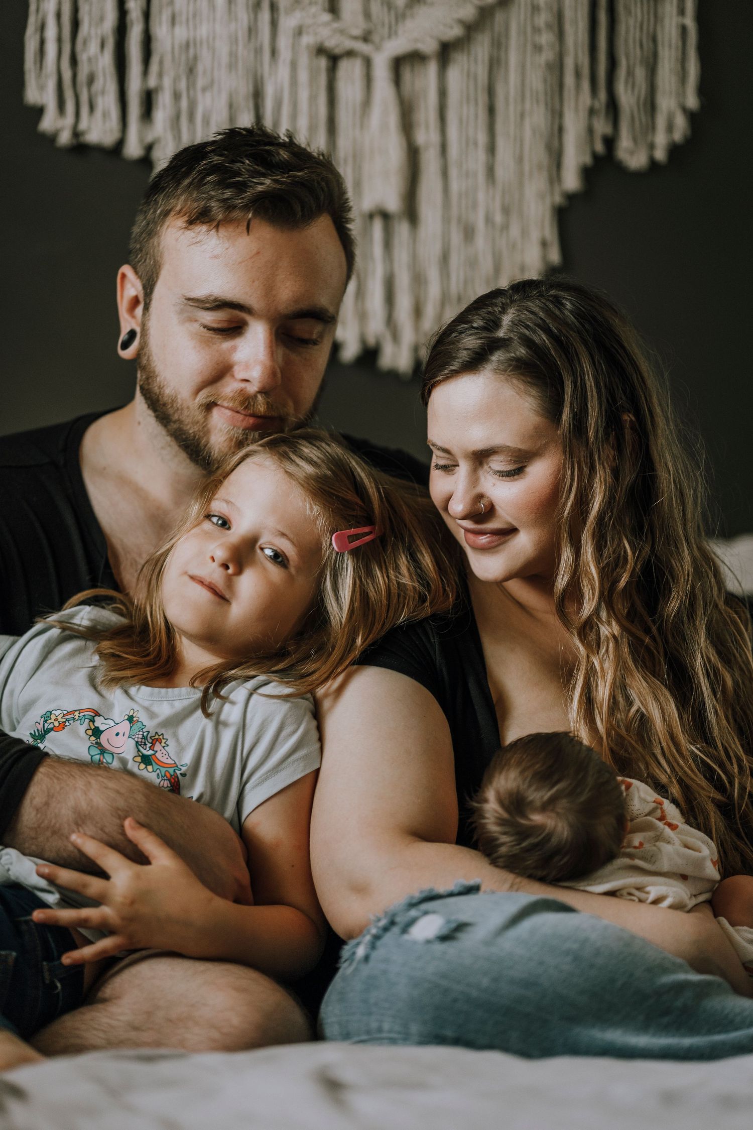 A tender family moment captured in moody lighting with a macrame wall hanging.