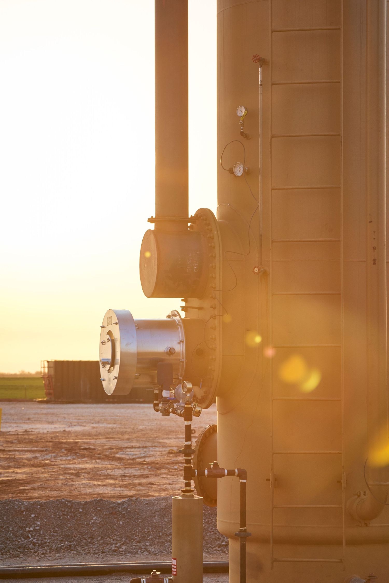 Oil and gas wellsite at sunrise with yellow sunrays
