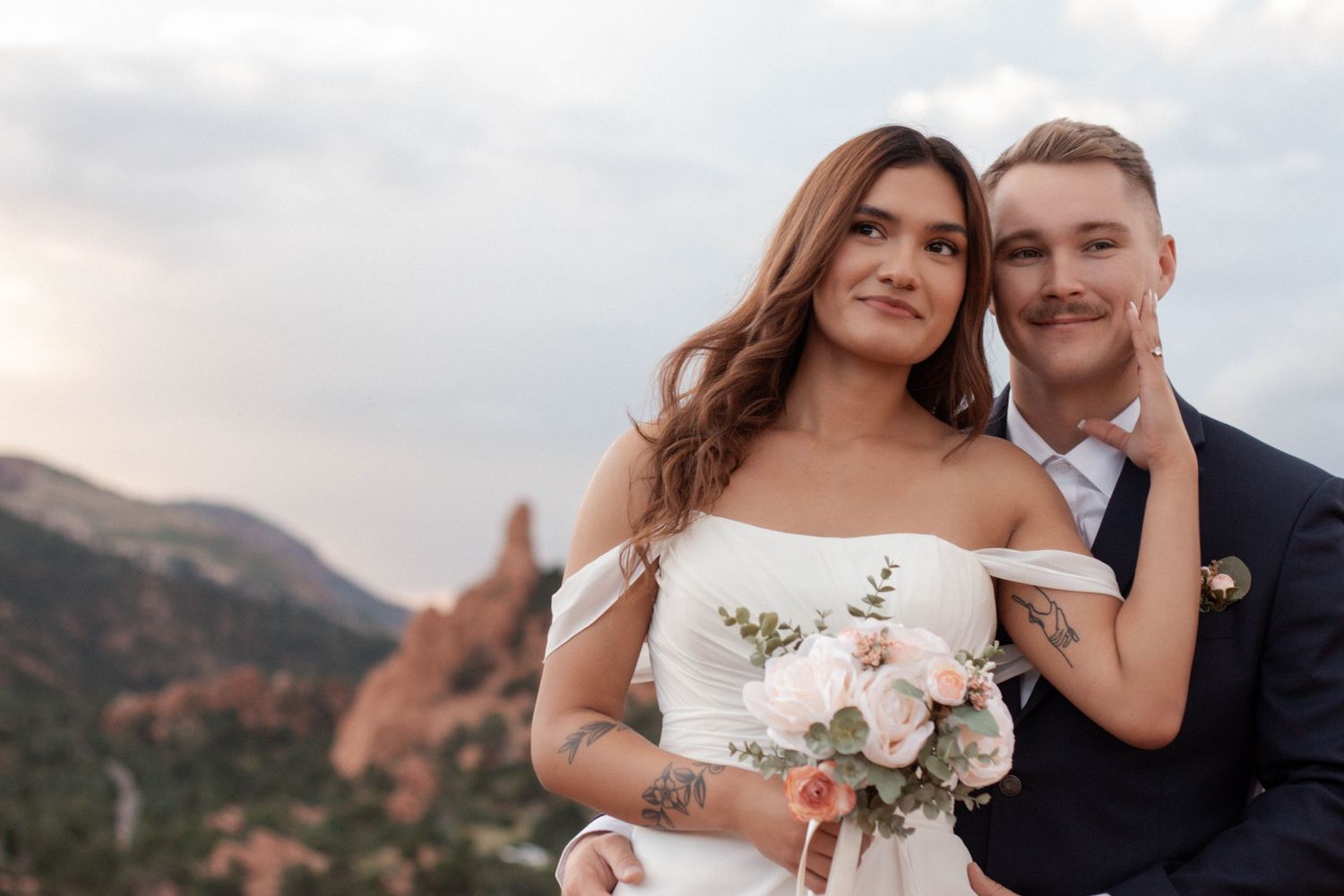 Wedding couple poses for a portrait at Garden of the Gods in Colorado Springs with mountain backdrop at sunset. Elopement photographer