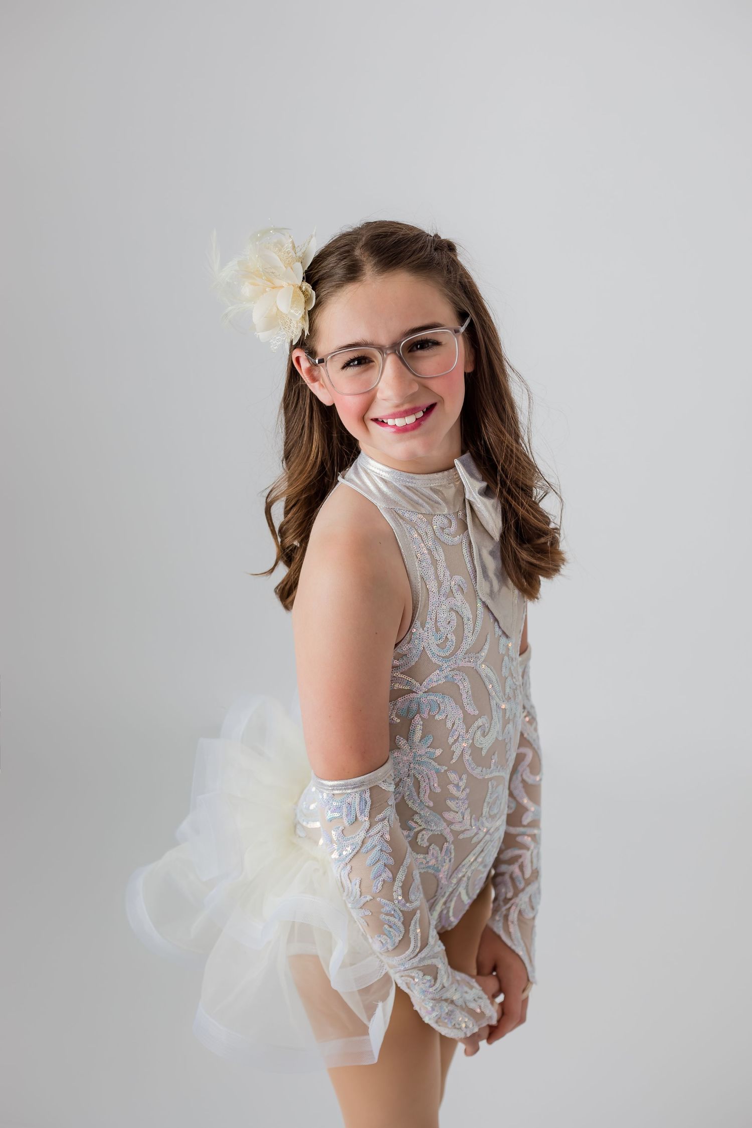 Simple white backdrop with a smiling dancer dressed in white lace smiling for her dance portraits.