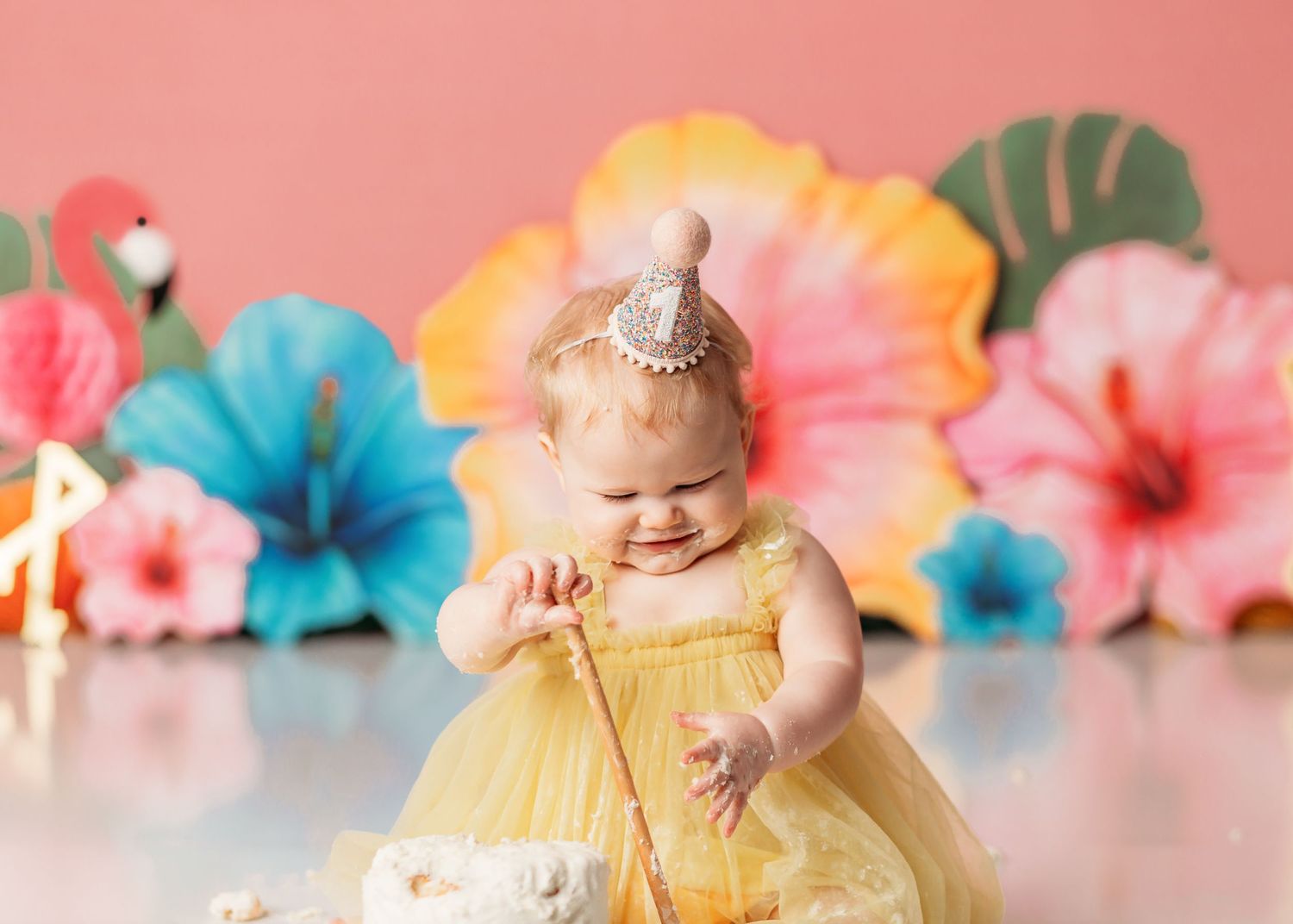 baby girl eating cake at her tropical theme cake smash in tulsa ok