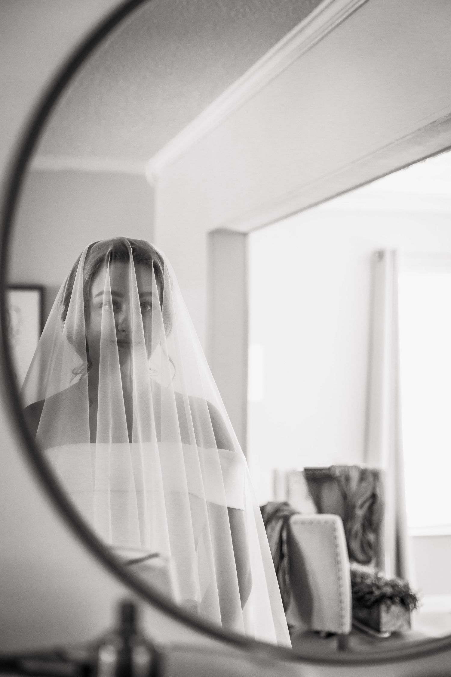 Black and white mirror reflection of bride wearing sheer wedding veil.