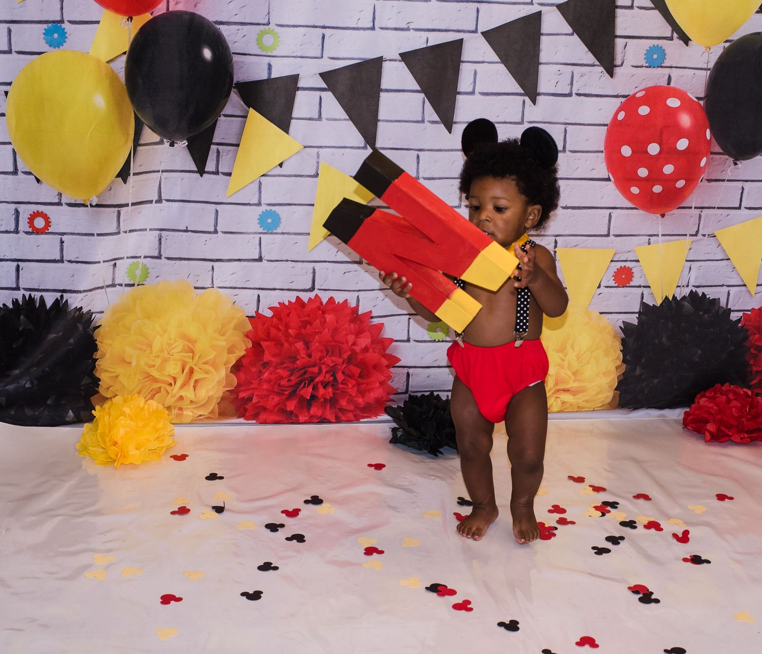 Festive party scene with brick wall backdrop, balloons, and yellow triangle banners.