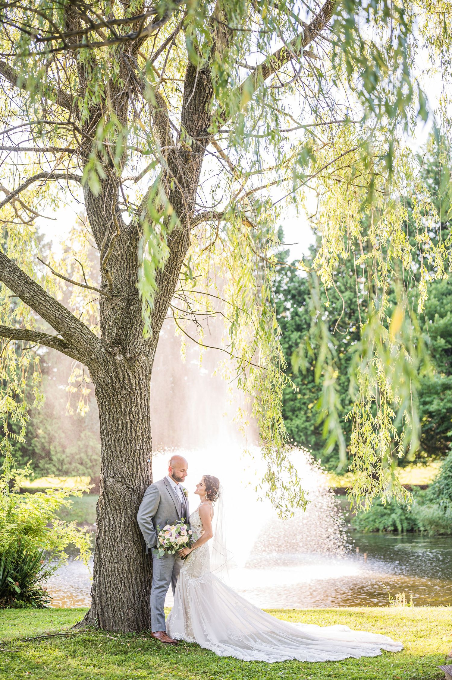 A couple leans against a tree, gazing into each other's eyes