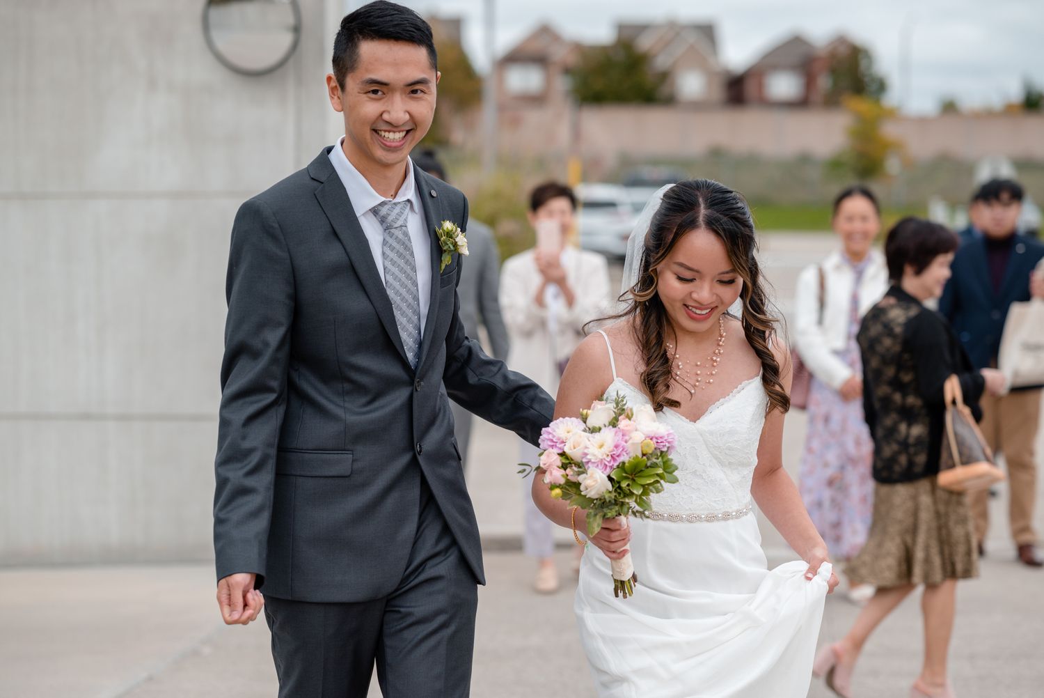 Newlyweds walking together while the bride holds a bouquet and her dress flows in the breeze.