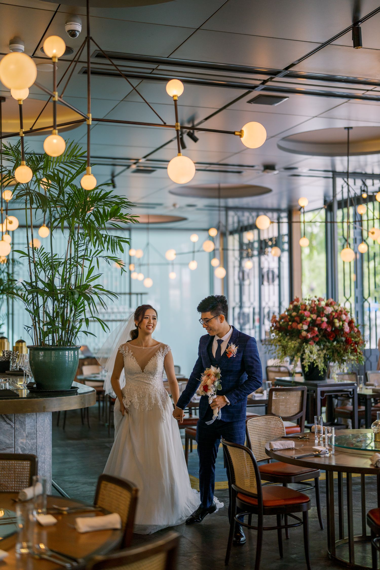 Modern restaurant interior with hanging lights and tropical plants creating an intimate atmosphere.