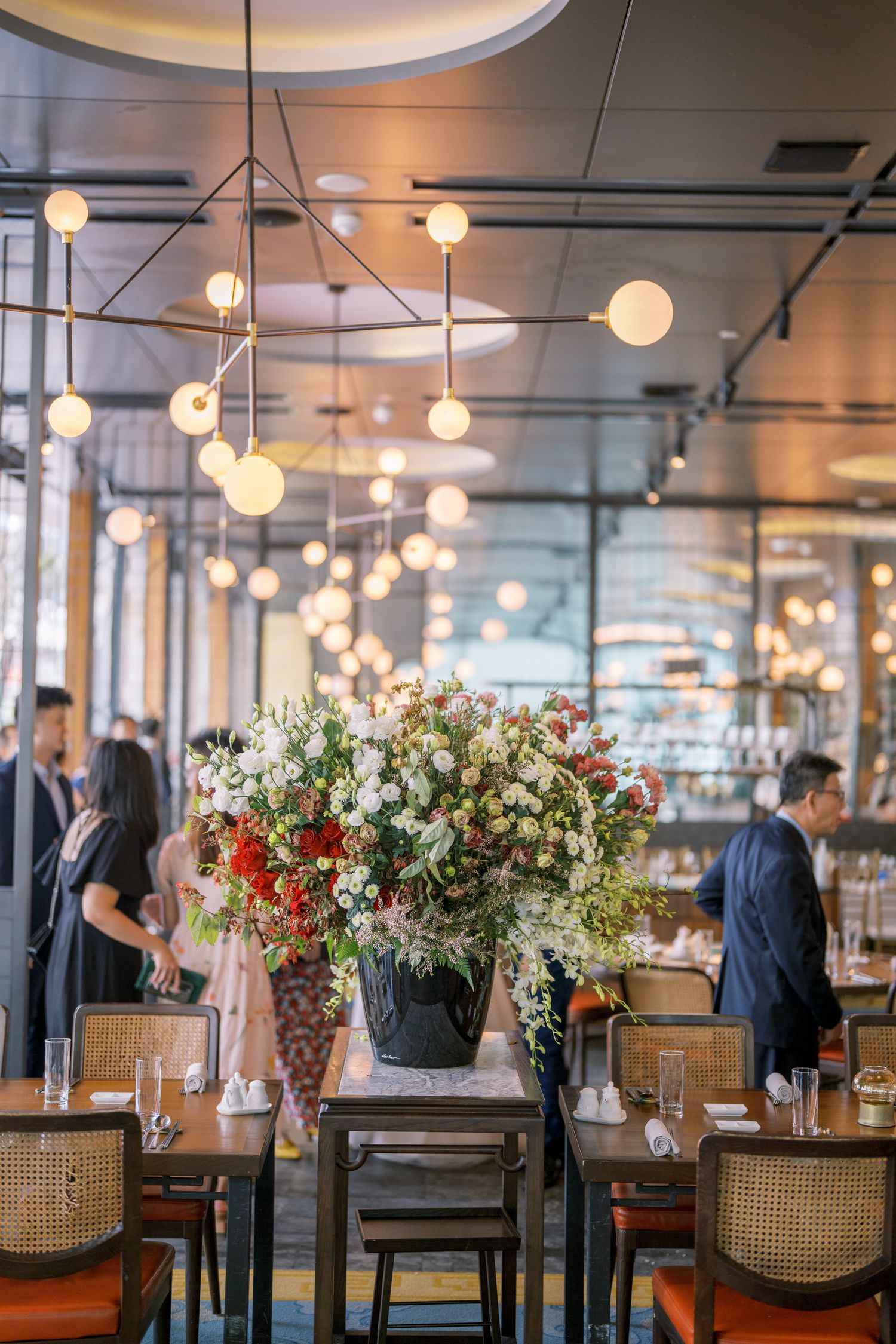 Restaurant interior with elegant floral centerpieces and hanging lights creating a romantic ambiance.