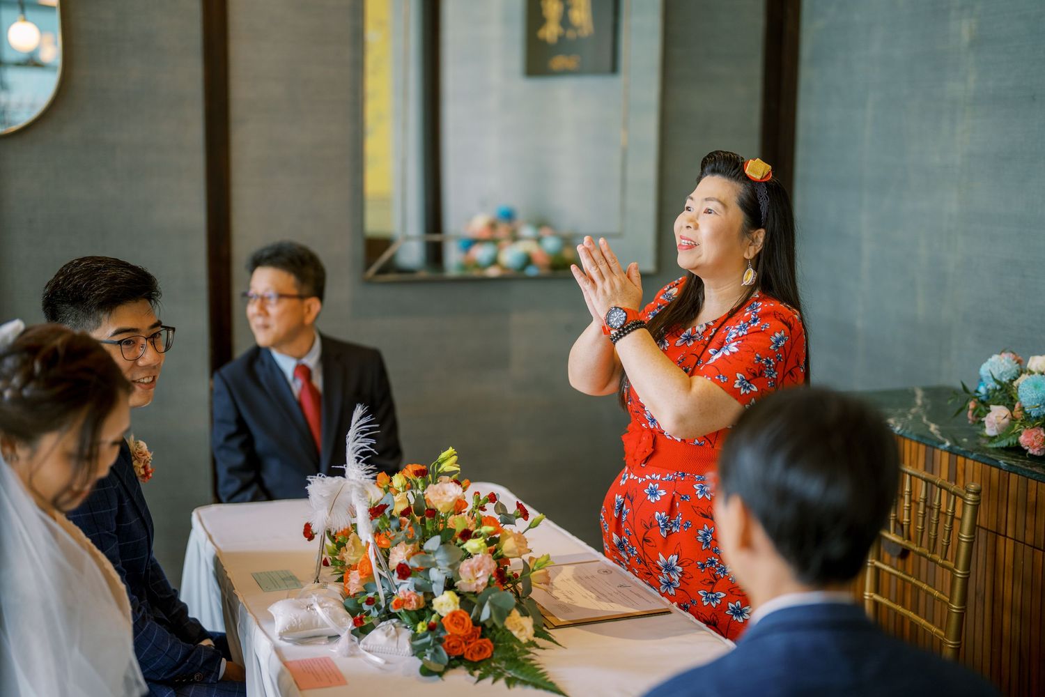 A wedding celebration with someone in red giving an animated speech at the reception.