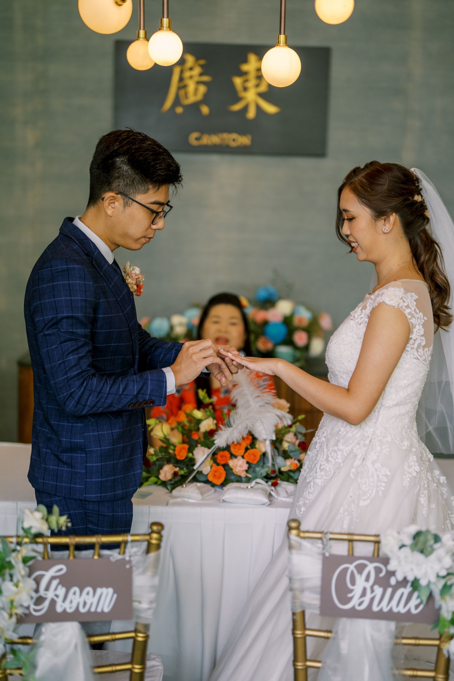 A couple exchanging documents during their wedding ceremony under golden Chinese characters.