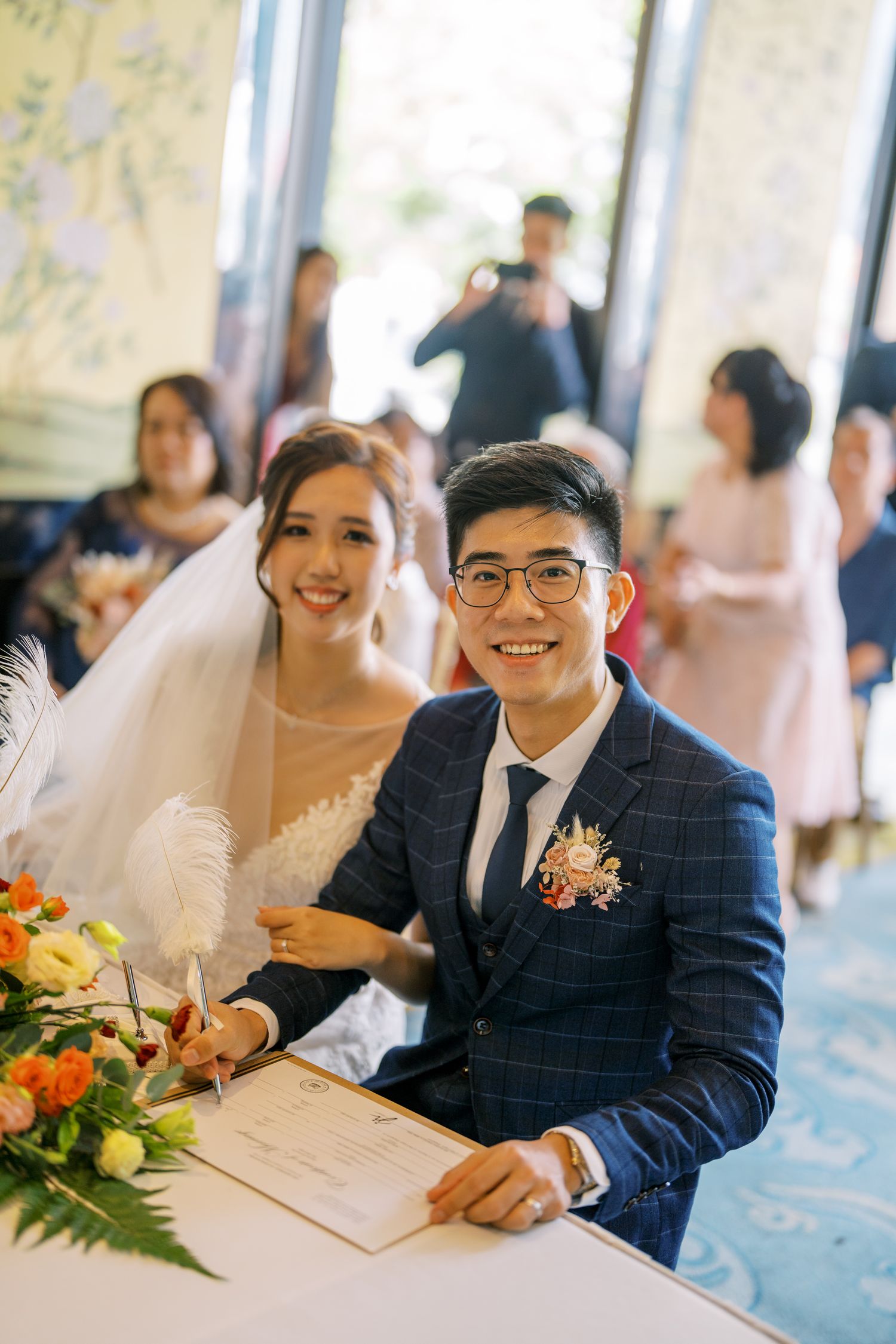 Wedding celebration in a bright room with floral decorations and table settings.