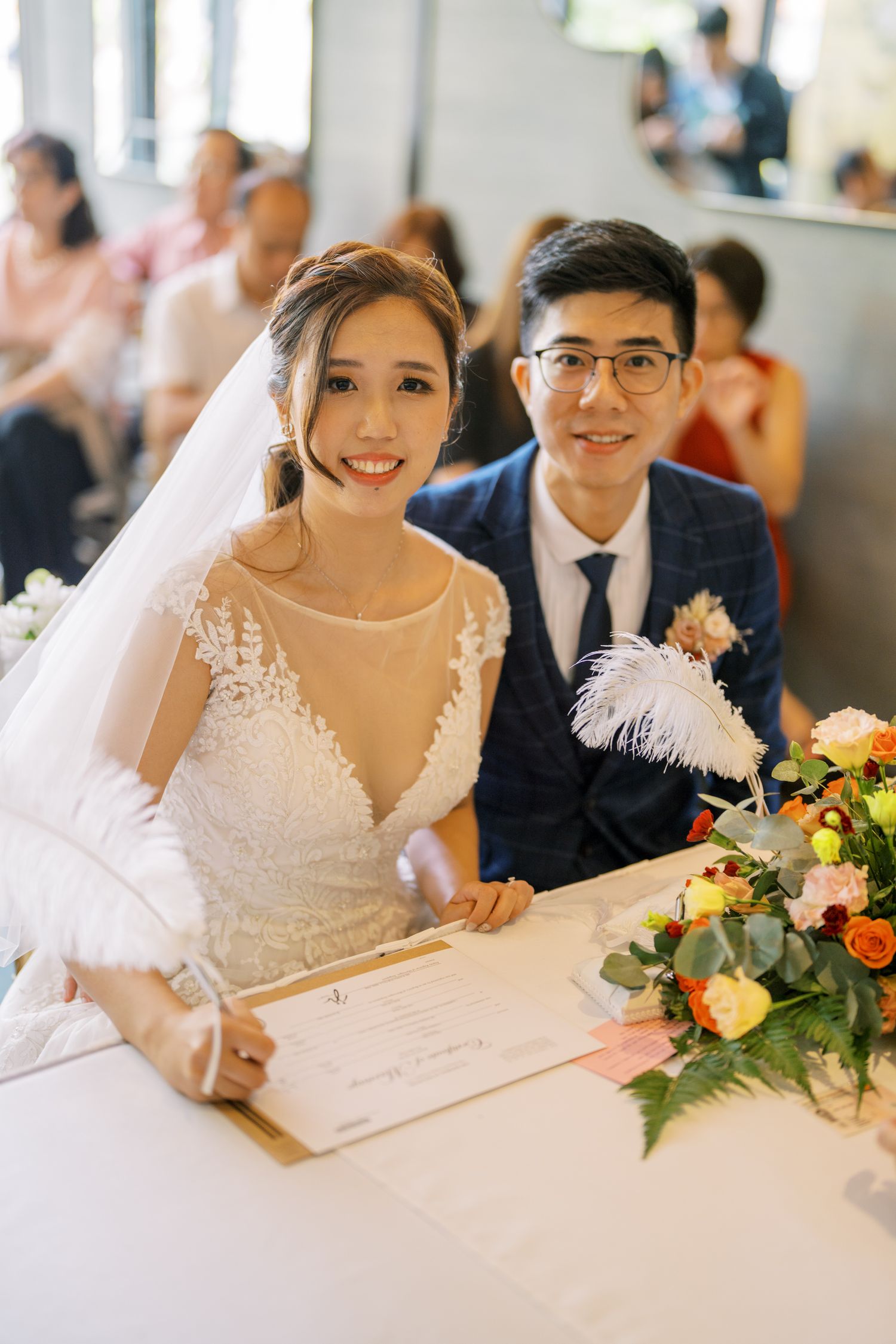 Wedding couple seated at a decorated table with floral arrangements.