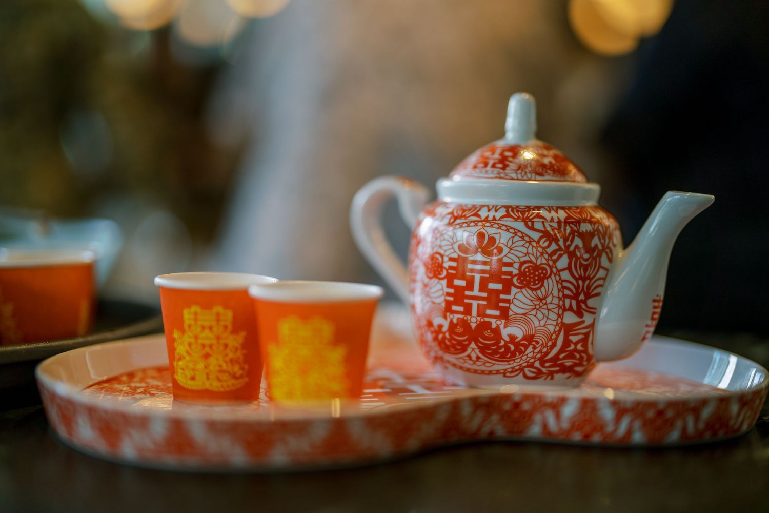 Traditional Chinese tea set with orange cups arranged on a dark table.