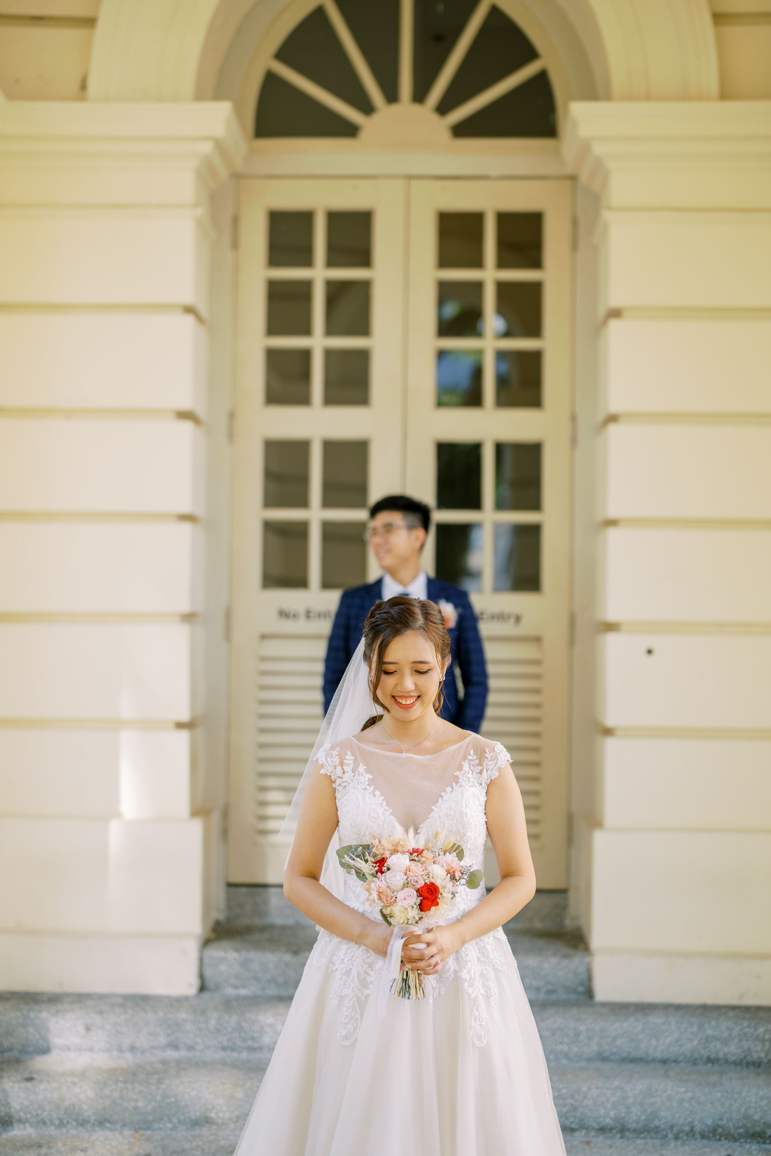 Elegant cream-colored building entrance with arched windows and classical architectural details.