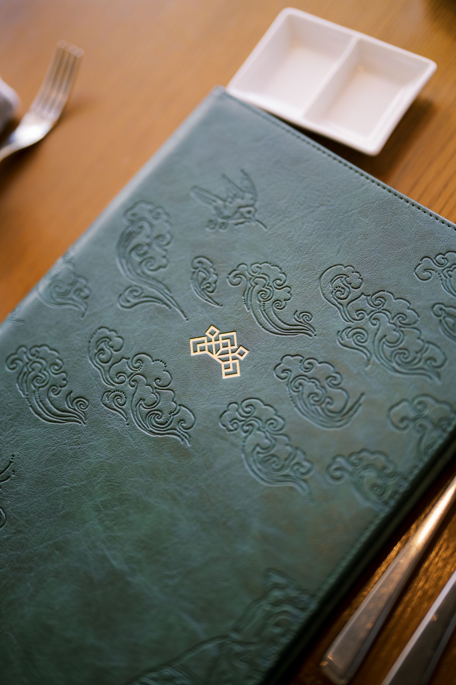 Dark green leather menu cover with embossed decorative patterns.