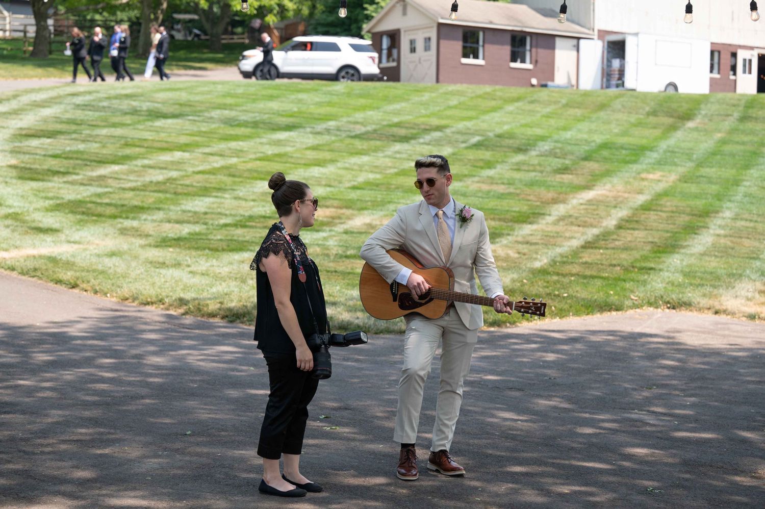 Musicians perform outdoors on a sunny day with houses visible in the background.