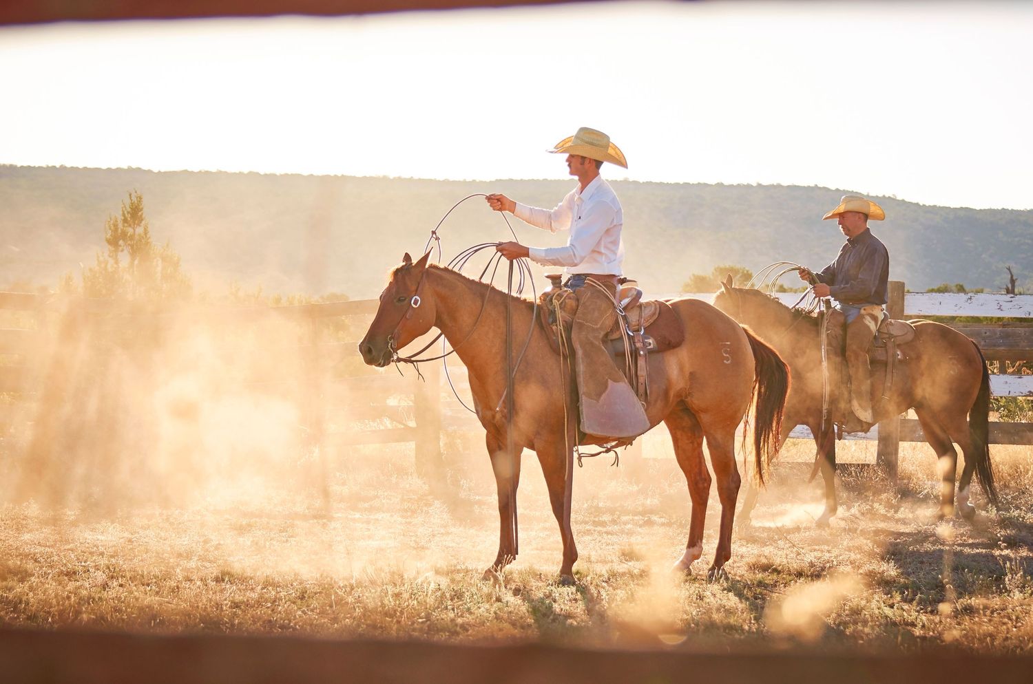 Cowboys in dusty roundpen with ropes