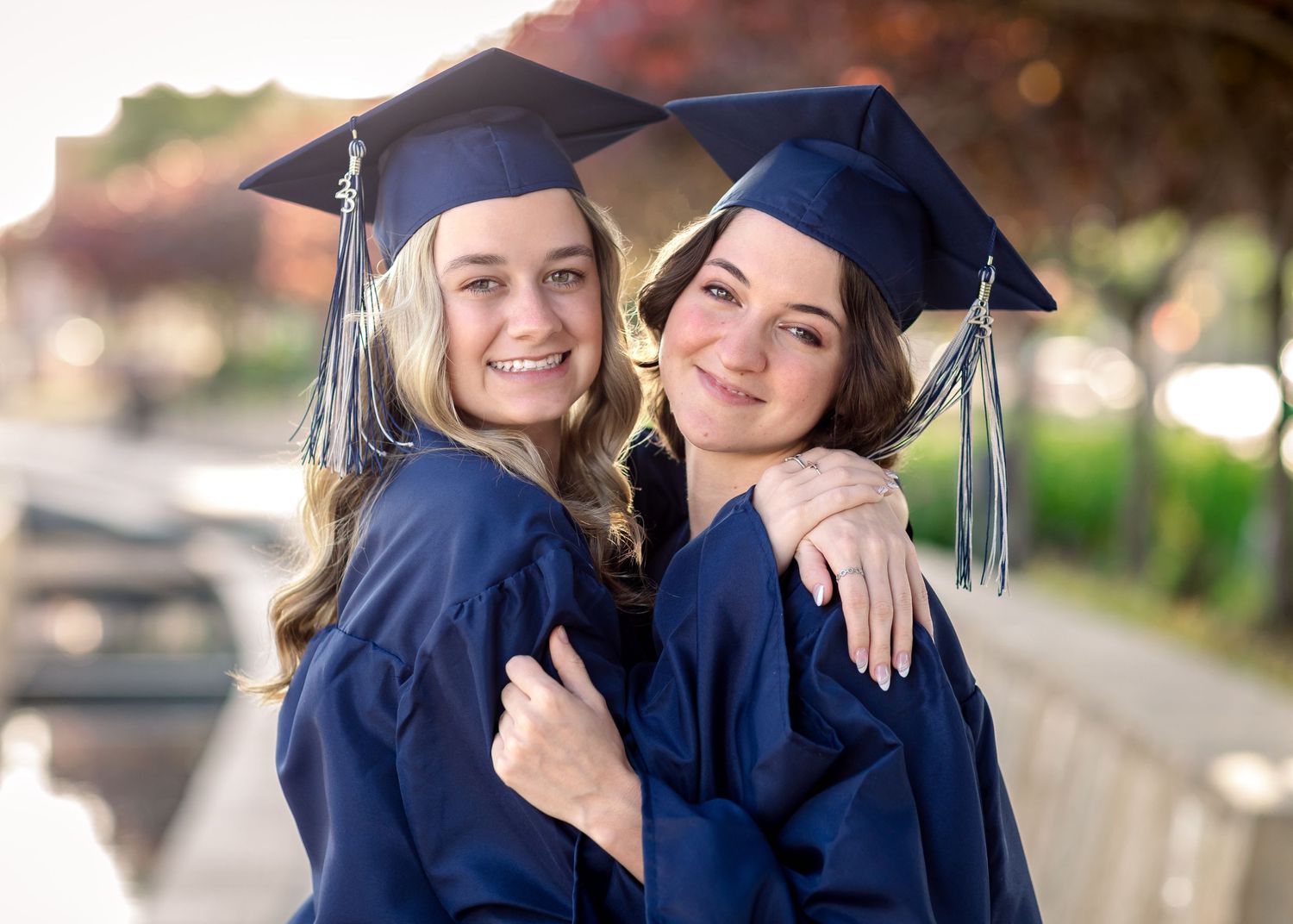 Graduation photos of two people embracing in navy blue caps and gowns.