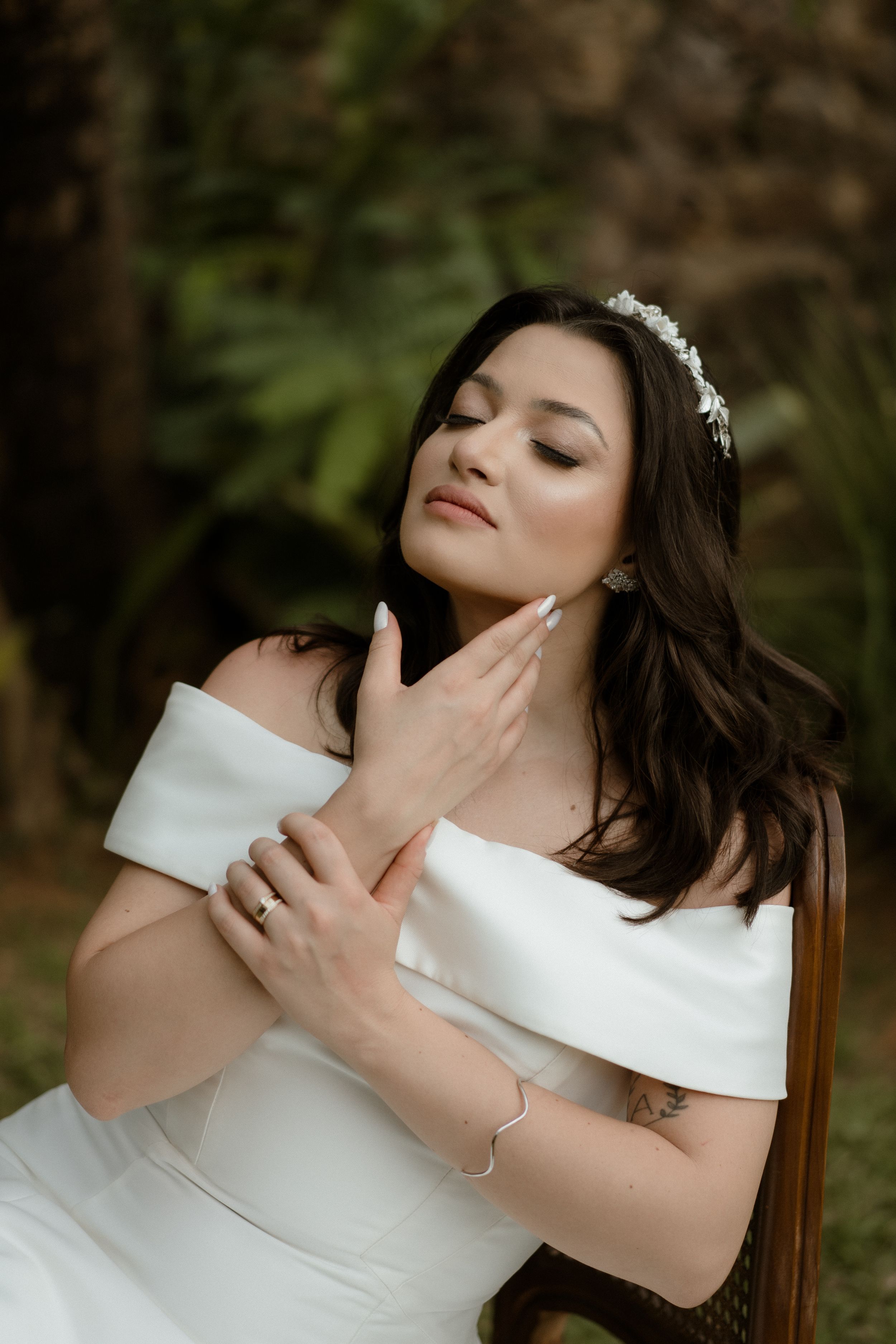 Elegant off-shoulder white wedding dress details in garden setting.