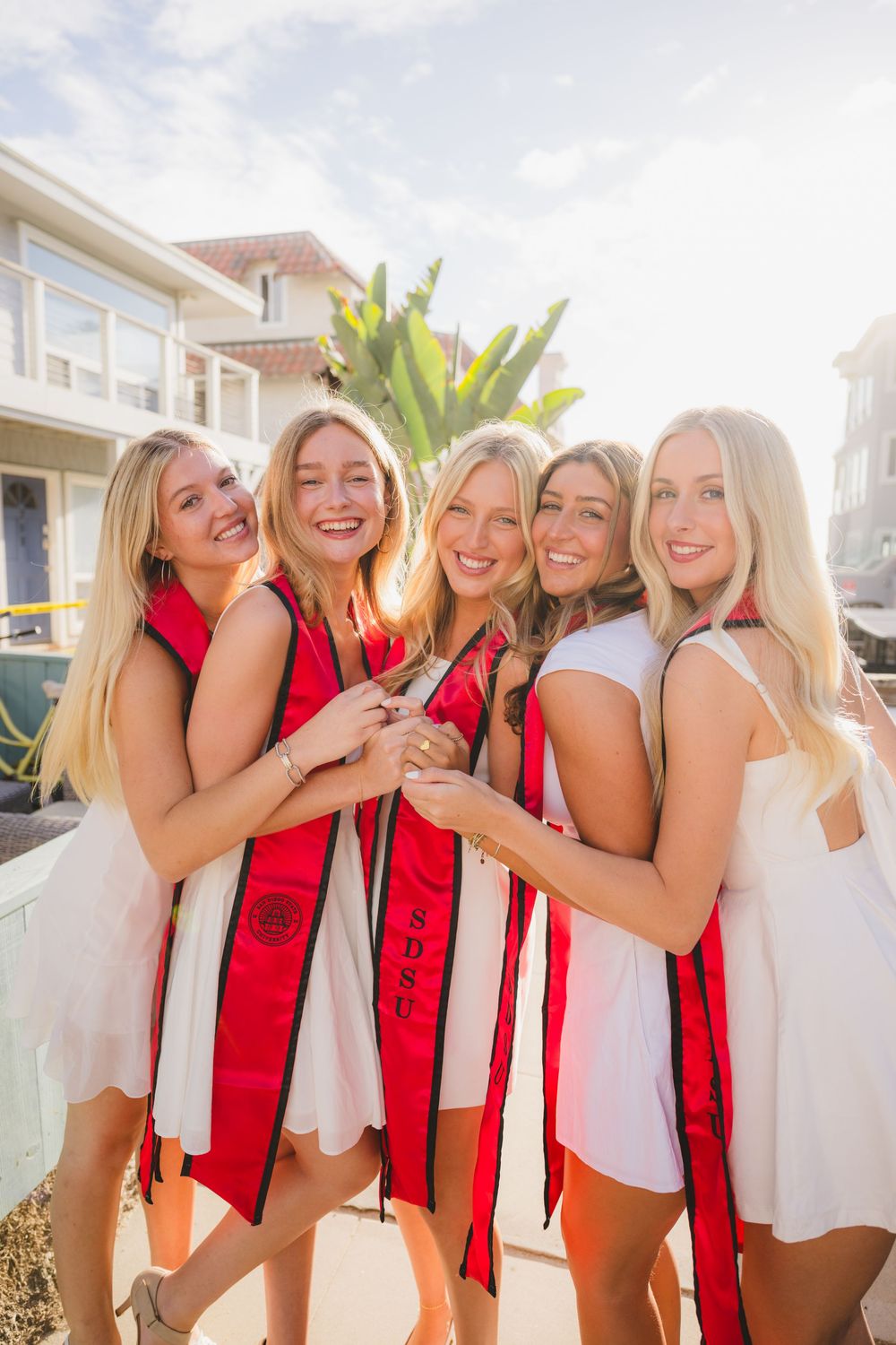 Group of SDSU grads hugging each other as they pose for their grad photos.