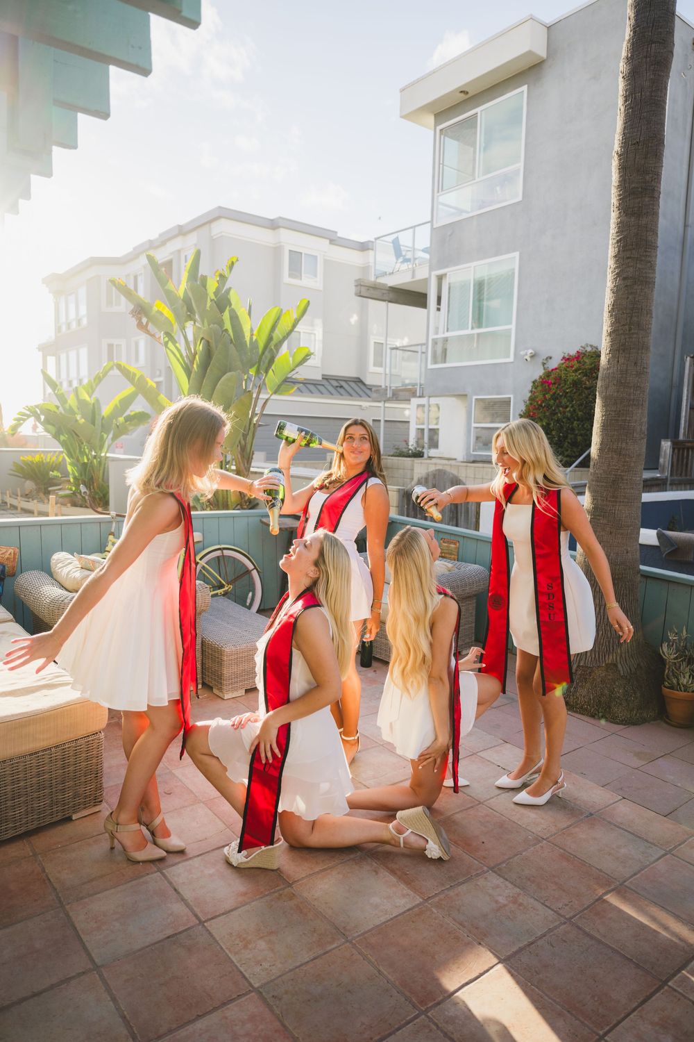 Group of SDSU grads pouring champagne and playing around as they pose for their grad photos.
