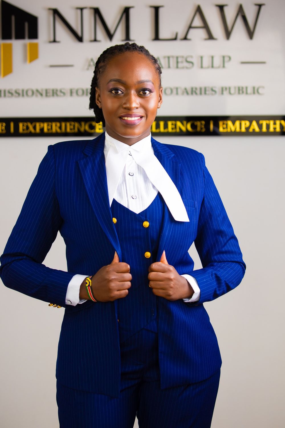 Professional in a navy blue suit with gold buttons and white bow tie in a law office in Nairobi Kenya