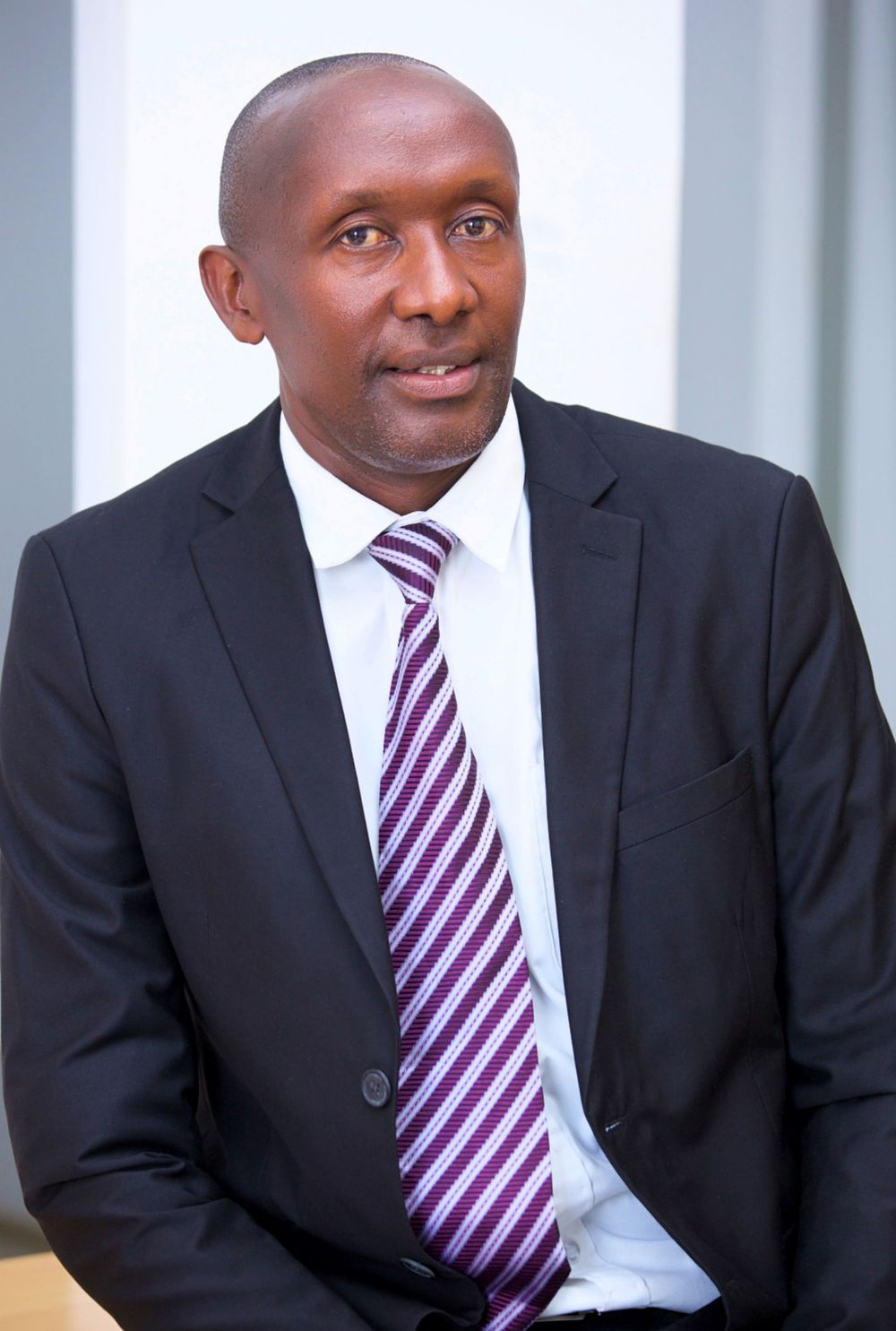 Professional in dark suit and striped tie photographed in office setting.