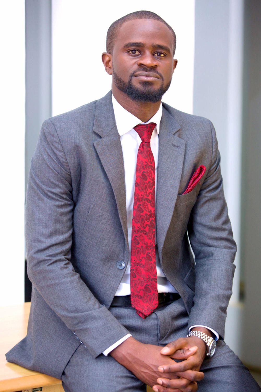 Business professional wearing grey suit with red tie in corporate portrait.