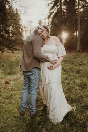 A couple shares tender moments at sunset in a forest meadow.