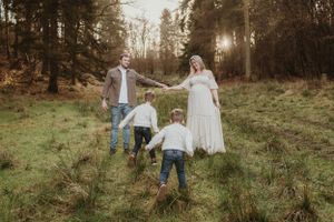 A family walks through a scenic forest meadow during golden hour.