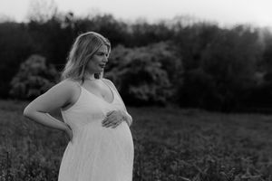 Black and white portrait of pregnant woman in natural outdoor setting.