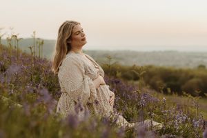 Joyful maternity portraits captured in a wildflower field during sunset.