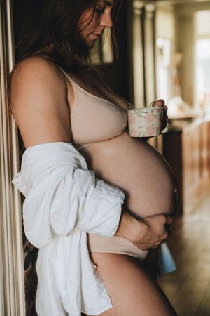 A series of artistic maternity photos showing a pregnant woman in white clothing by a window.