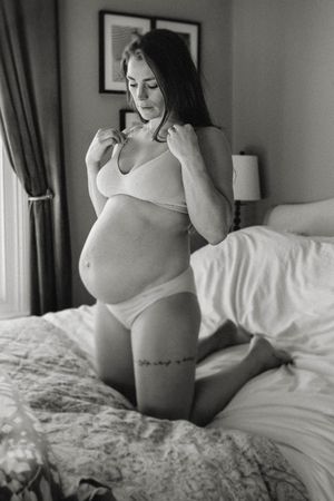Woman in white lingerie poses on bed in intimate black and white boudoir photo series.