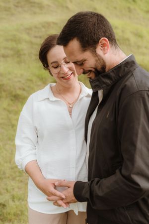 Intimate outdoor photo session with casual white and black attire on a grassy hillside.