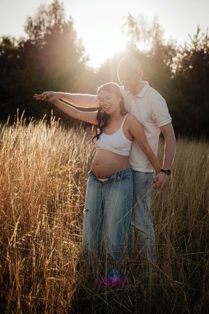 A couple shares an intimate moment in a golden wheat field at sunset, creating a romantic silhouette against the warm light.