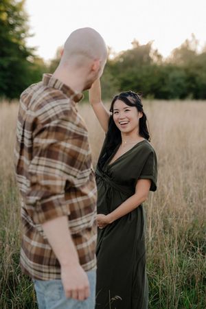 A couple dances playfully together in a golden field during sunset.