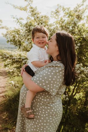 Sweet outdoor family moment captured in golden sunlight among blooming trees.