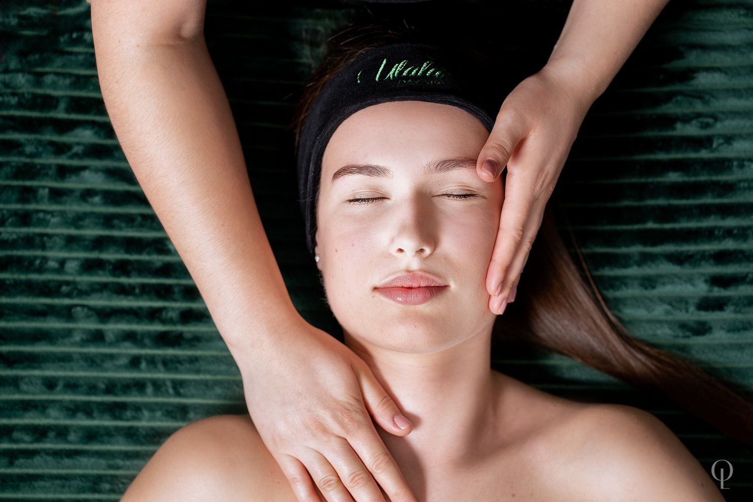 Relaxing spa facial massage treatment on green textured background.