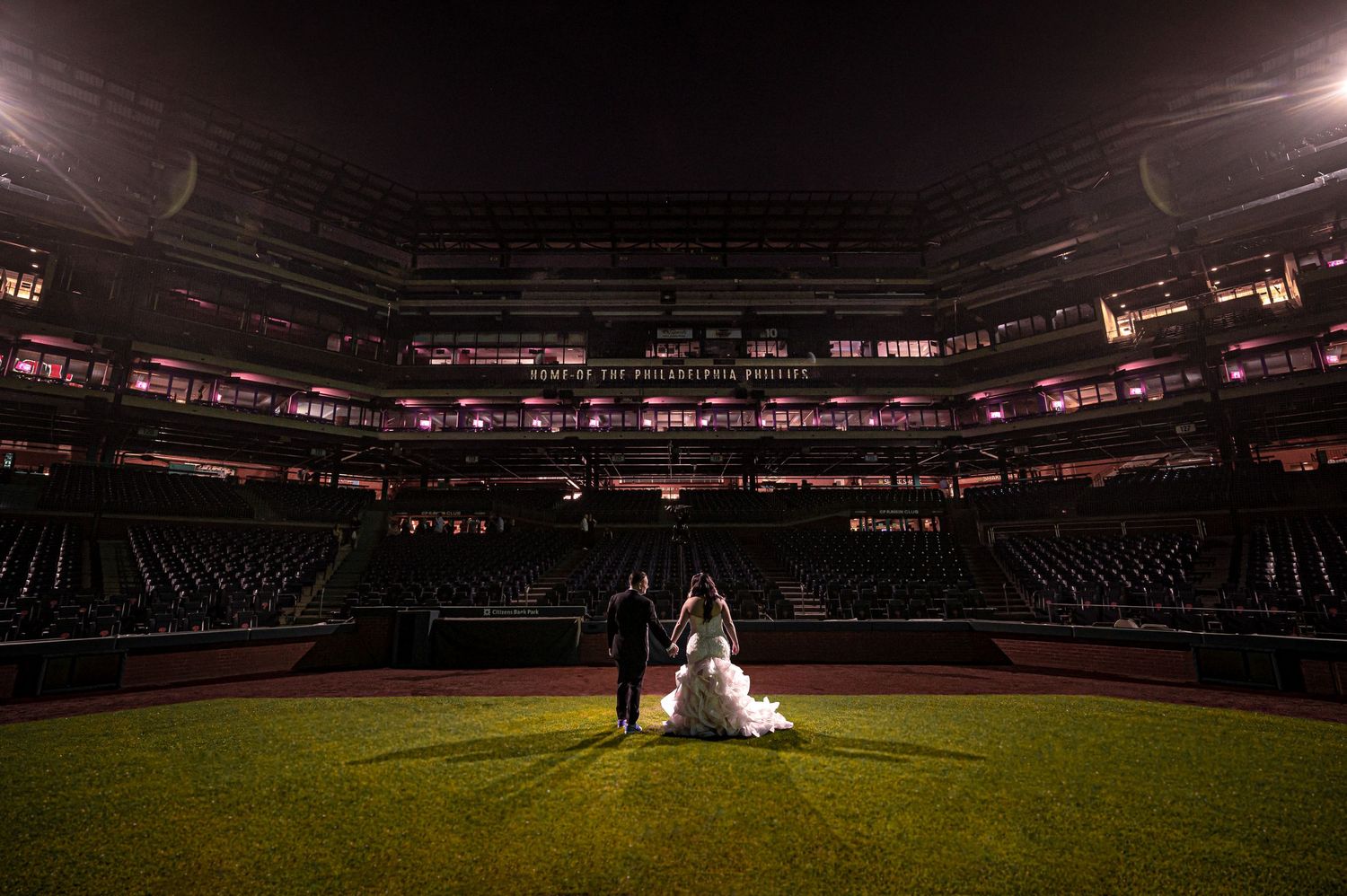 Dramatic nighttime wedding portrait on illuminated baseball field.  Night shot in Citizens Bank Park.