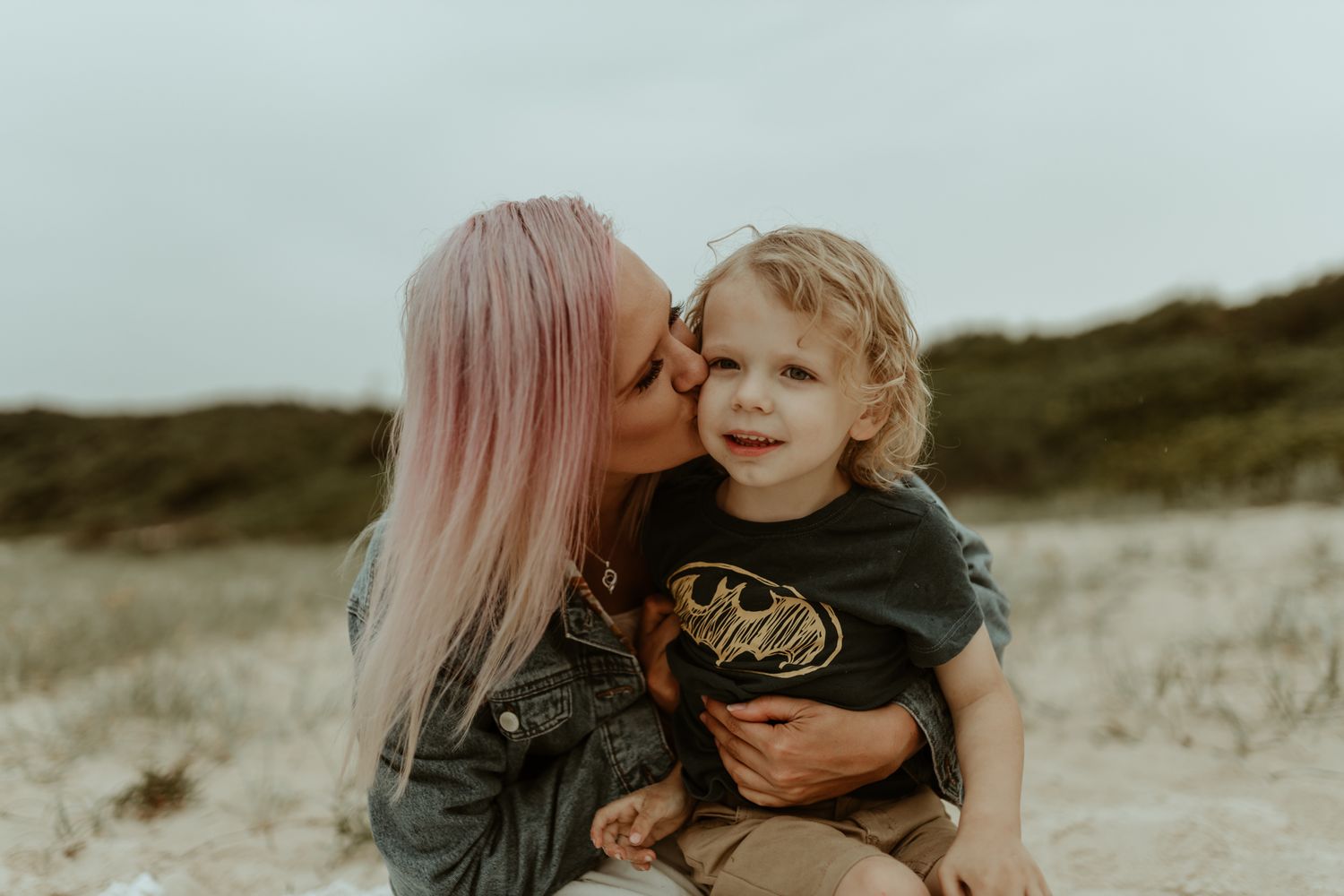 A tender beach moment shared between parent and child during a moody sunset session.