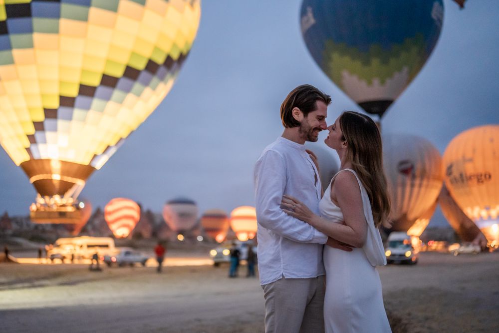 A romantic moment at twilight with illuminated hot air balloons glowing in the background.