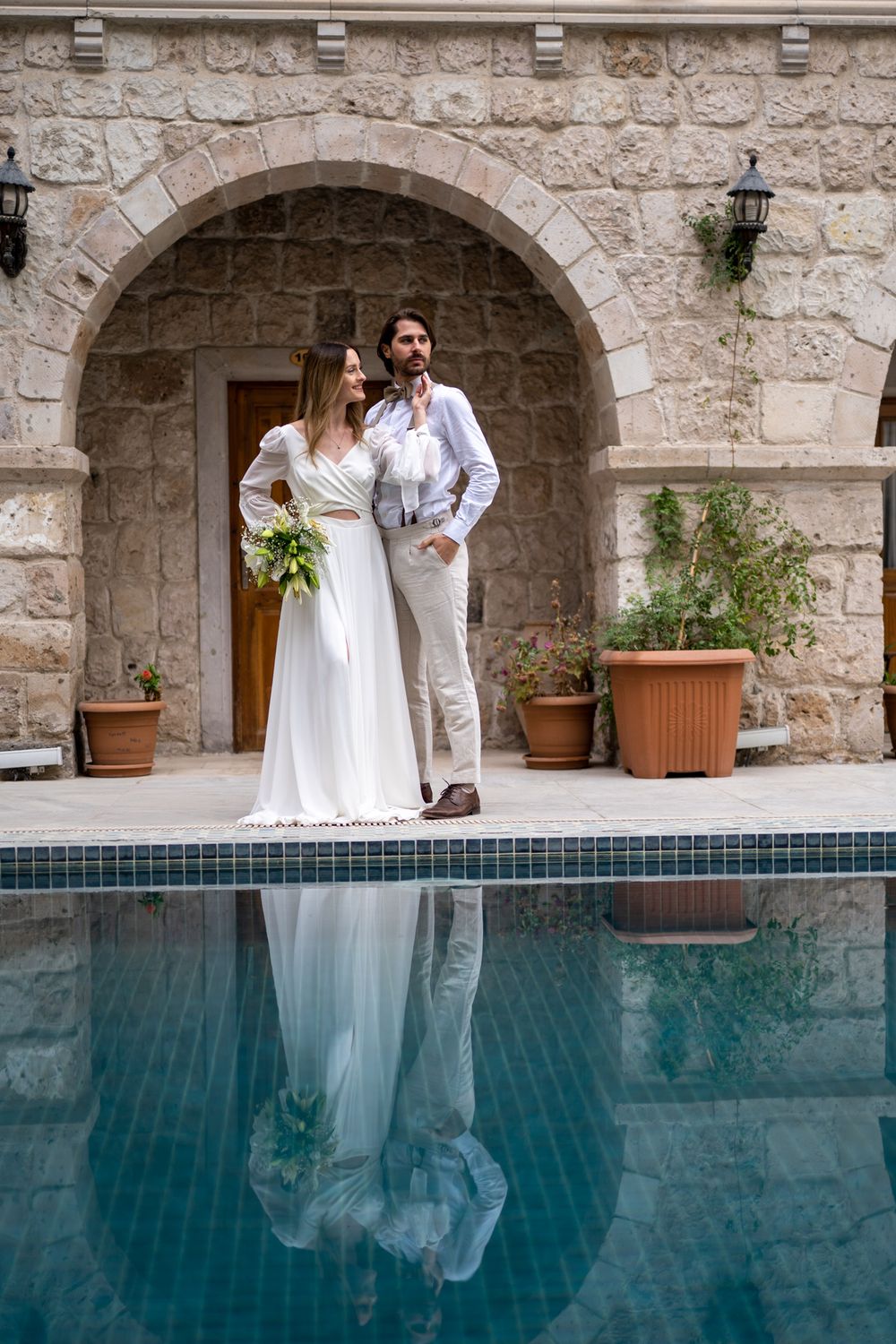 A reflection in a pool creates a mirror image against stone archways and architecture.