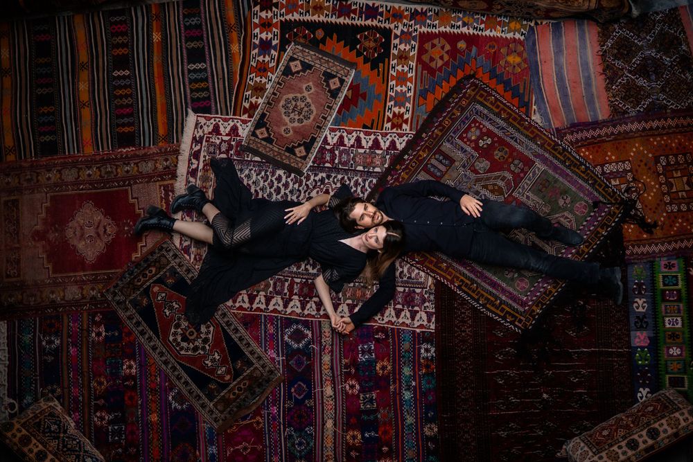 A couple lying on colorful Turkish carpets creating an artistic overhead composition.