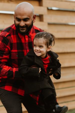 A joyful moment shared in matching red and black buffalo plaid outfits against a wooden wall backdrop.