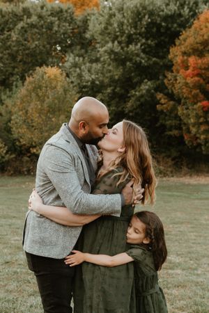 Sweet family moment captured during fall photo session with autumn colors in background.